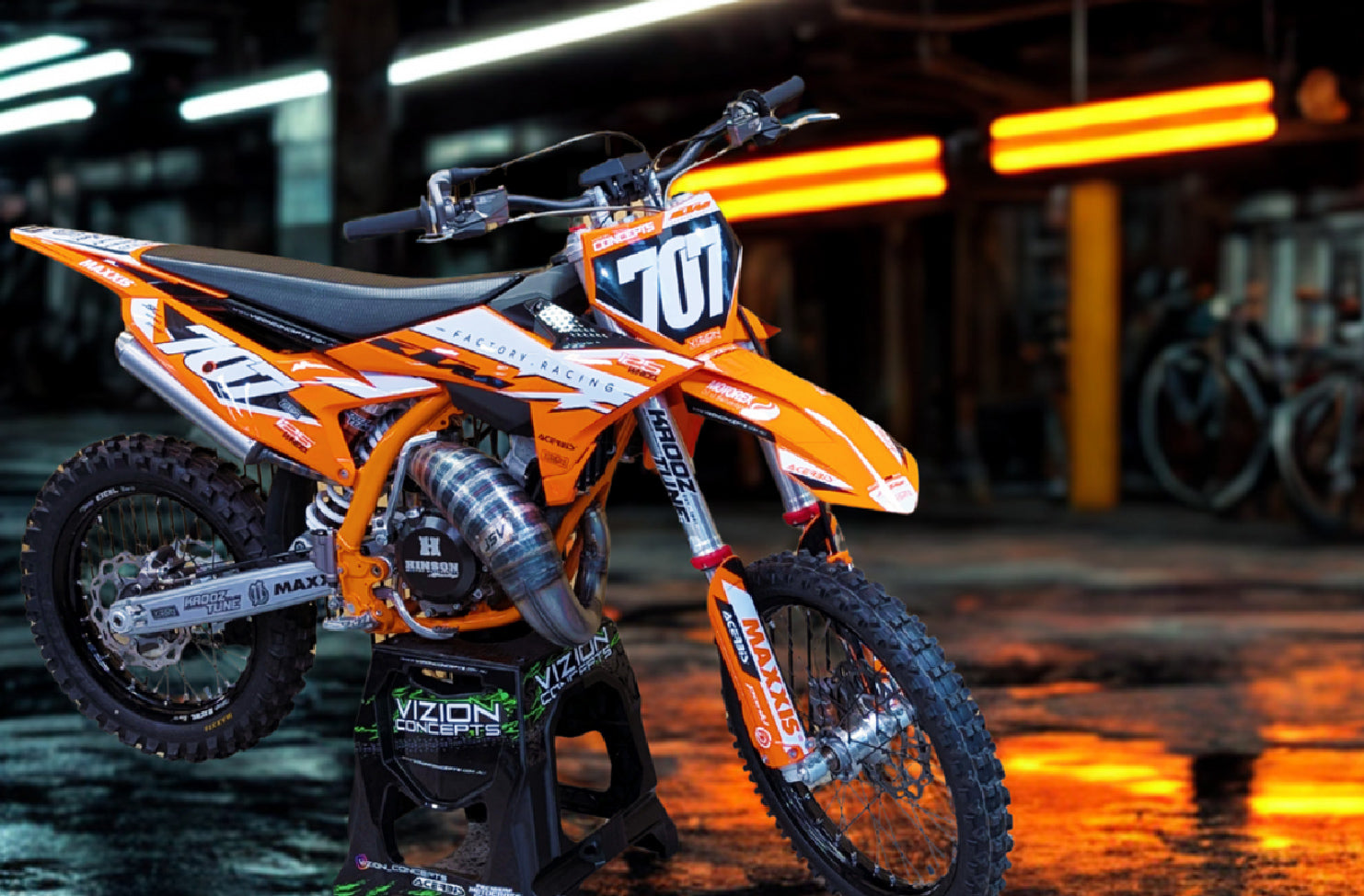 Orange dirt bike with visible branding on a wet surface at night.